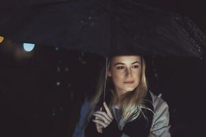 Thoughtful woman outdoors on rainy night photo