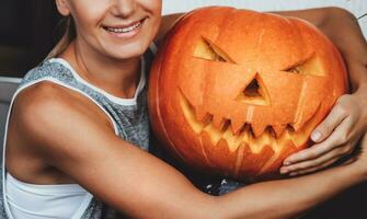 Happy girl with carved Halloween pumpkin photo