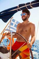 Happy guy behind wheel of sailboat photo