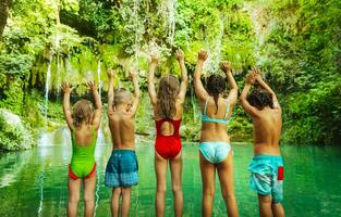 Happy children jumping to the lake photo