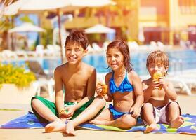 Three kids eating near pool photo