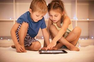 Two happy children playing on the tablet photo