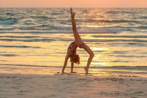adolescente niña haciendo yoga en el playa foto