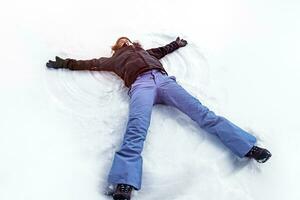 Young female making snow angel photo