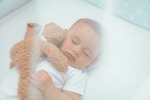 Cute baby boy sleeping with soft toy photo
