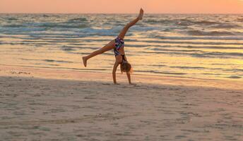 linda niña haciendo gimnasia en el playa foto