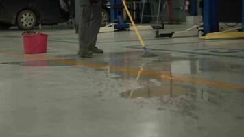 Worker man clean dirty floor in car-care center. video