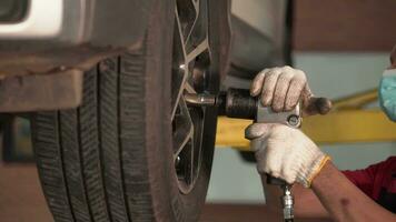 Close-up of a mechanic's hand turning a nut to change a tire. video