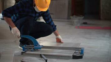 Asia men worker builder cutting tiles using a tile cutting machine at site . video