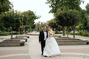 the groom in a brown suit and the bride in a white dress photo