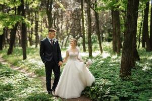 the groom and the bride are walking in the forest photo