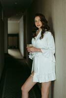 brown-haired girl in the morning in a bathrobe in the hotel corridor with photo