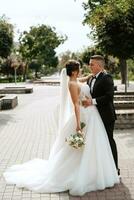 el novio con traje marrón y la novia con vestido blanco foto