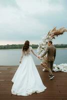 el primero Boda danza de el novia y novio en el muelle cerca el río foto