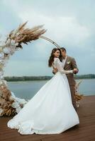 the first wedding dance of the bride and groom on the pier near the river photo