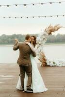 the first wedding dance of the bride and groom on the pier near the river photo