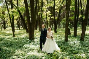 the groom and the bride are walking in the forest photo