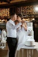 los recién casados felizmente cortan y prueban el pastel de bodas foto