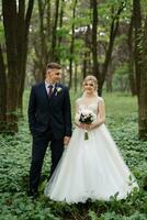 the groom and the bride are walking in the forest photo