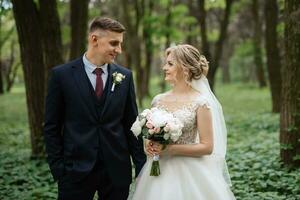 the groom and the bride are walking in the forest photo