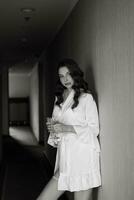 brown-haired girl in the morning in a bathrobe in the hotel corridor with photo