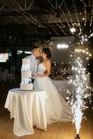 los recién casados felizmente cortan y prueban el pastel de bodas foto