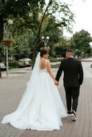 the groom in a brown suit and the bride in a white dress photo