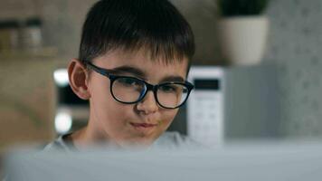 Stay at home, leisure at home, technologies for children, self isolation. A cheerful boy in glasses is watching cartoons while sitting at home using a laptop and eating popcorn. Close-up video