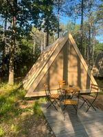 Wooden bungalow house with porch in nature. Longosphere glamping. A gable roof bungalow at the campsite. photo