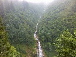 Ayder Plateau and natural Gelintulu Waterfall with foggy forest landscape in Rize, Turkey. Noise and grain included. Selective focus. photo