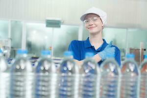 Young happy woman worker in factory checking water gallons before shipment. photo