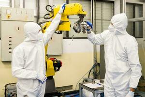 técnico ingenieros cheque robot brazos y reparar automático robótico máquinas a el industrial fábrica, trabajadores trabajando con enfocado reparando robótico brazos en el industria. foto