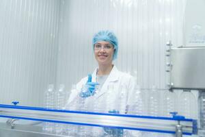 Young happy woman worker in factory checking water gallons before shipment. photo