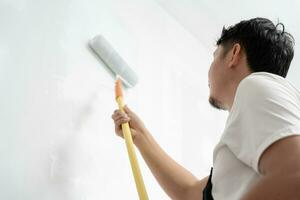 painter man, brush in hand for products to restore and paint the wall, indoor the building site of a house, wall during painting, renovation, painting, contractor, Architect, construction worker photo