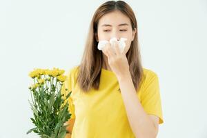 polen alergias, asiático joven mujer estornudos en un pañuelo o soplo en un limpiar, alérgico a salvaje primavera flores o flores durante primavera. alérgico reacción, respiratorio sistema problemas foto