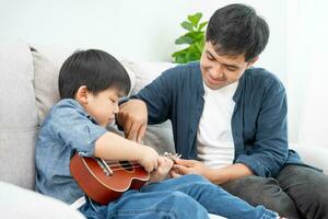 contento soltero padre jugando aprendizaje música con el pequeño chico. gracioso familia es contento y emocionado en el casa. padre y hijo teniendo divertido gasto hora juntos. vacante tiempo, fiesta foto