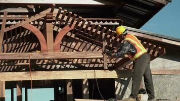 Young carpenter roofer builder working on roof structure on construction site. video