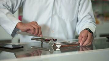 A male pharmacist is counting pills on counting drugstore. video