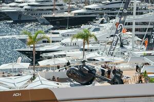 Monaco, Monte Carlo, 27 September 2022 - Rich clients visitors examine a helicopter standing on the deck of a yacht club, the largest fair yacht show, port Hercules, yacht brokers, sunny weather photo