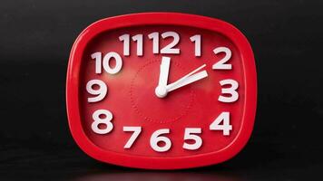 avvicinamento di rosso orologio tempo periodo su nero sfondo. un' rosso parete orologio in esecuzione veloce. video