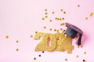 números 2024 con graduado sombrero y estrellas en un rosado antecedentes. contento nuevo año concepto foto