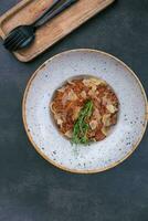Bolognese in a bowl decorated dry tomato and microgreen on a dark table top view, flat lay photo