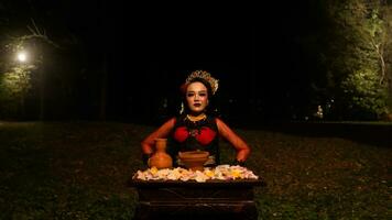 un hembra bailarín realiza un ritual ese crea un mágico y místico atmósfera en frente de flor ofrendas foto