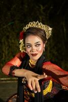 An Asian dancer in a red costume poses very flexibly on a stage photo