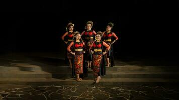 a group of dancers stand and unite in red costumes that show unity photo