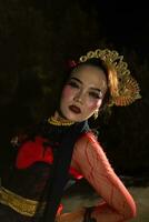a Balinese woman wears heavy makeup with rosy red lips and sharp hair when posing photo