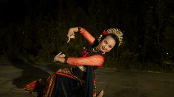 a Balinese dancer wearing gold jewelry and dancing with confidence on the stage photo