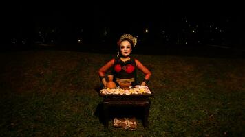 un hembra bailarín realiza un ritual ese crea un mágico y místico atmósfera en frente de flor ofrendas foto