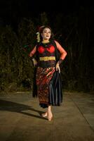 An Indonesian dancer in a gold and red costume stands very gracefully photo