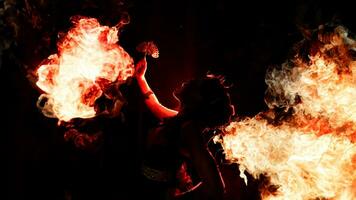 the silhouette of a female dancer holding sparkling jewelry and looking sharp in the dark with fire burning in the background photo